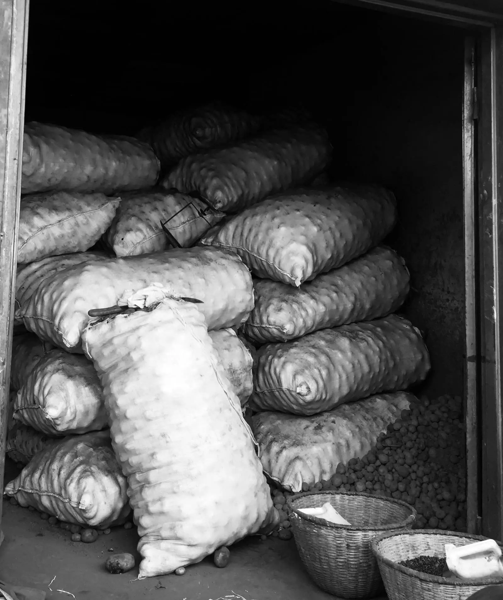 Woven sacks of produce stacked high in a storeroom
